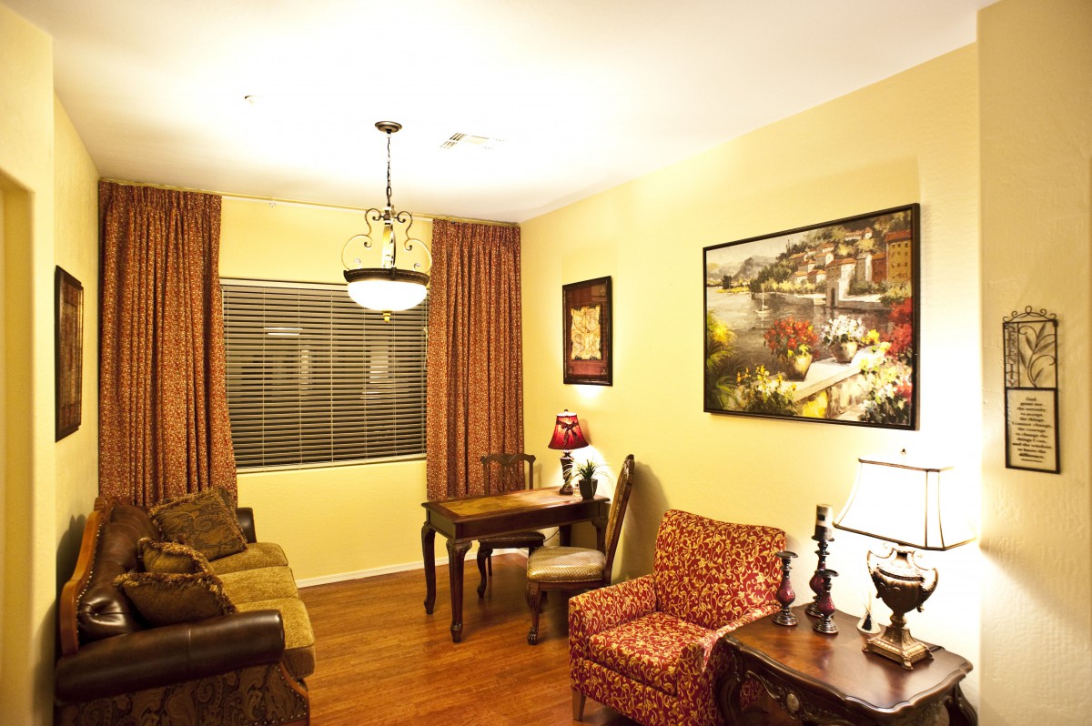 A cozy living room with warm lighting and classic decor, featuring a sofa, table, and chairs.