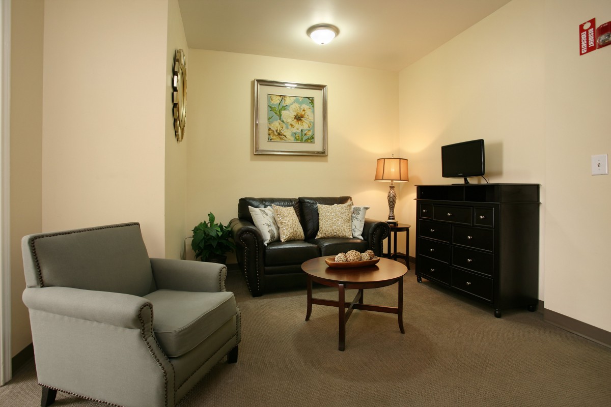 A cozy living room with a sofa, armchair, and a coffee table under soft lighting.