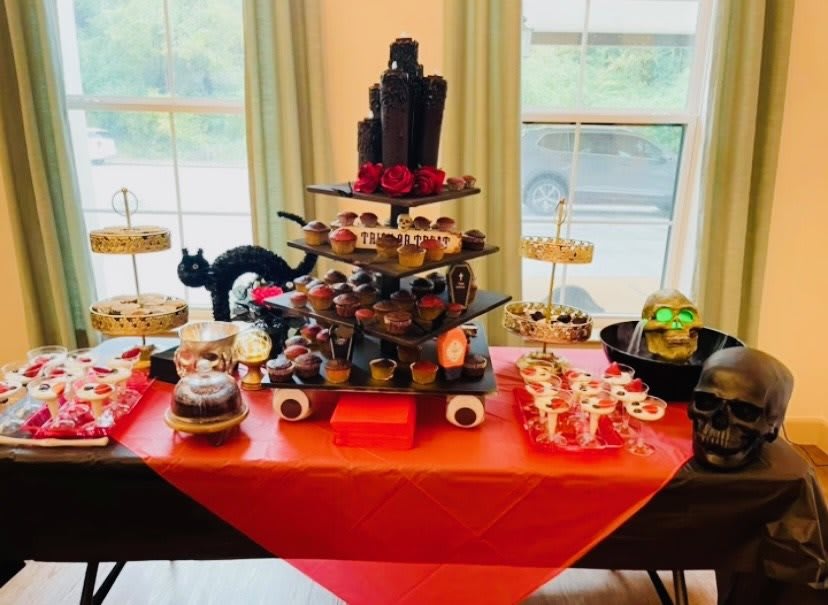A festive Halloween dessert table with various themed treats and decorations.