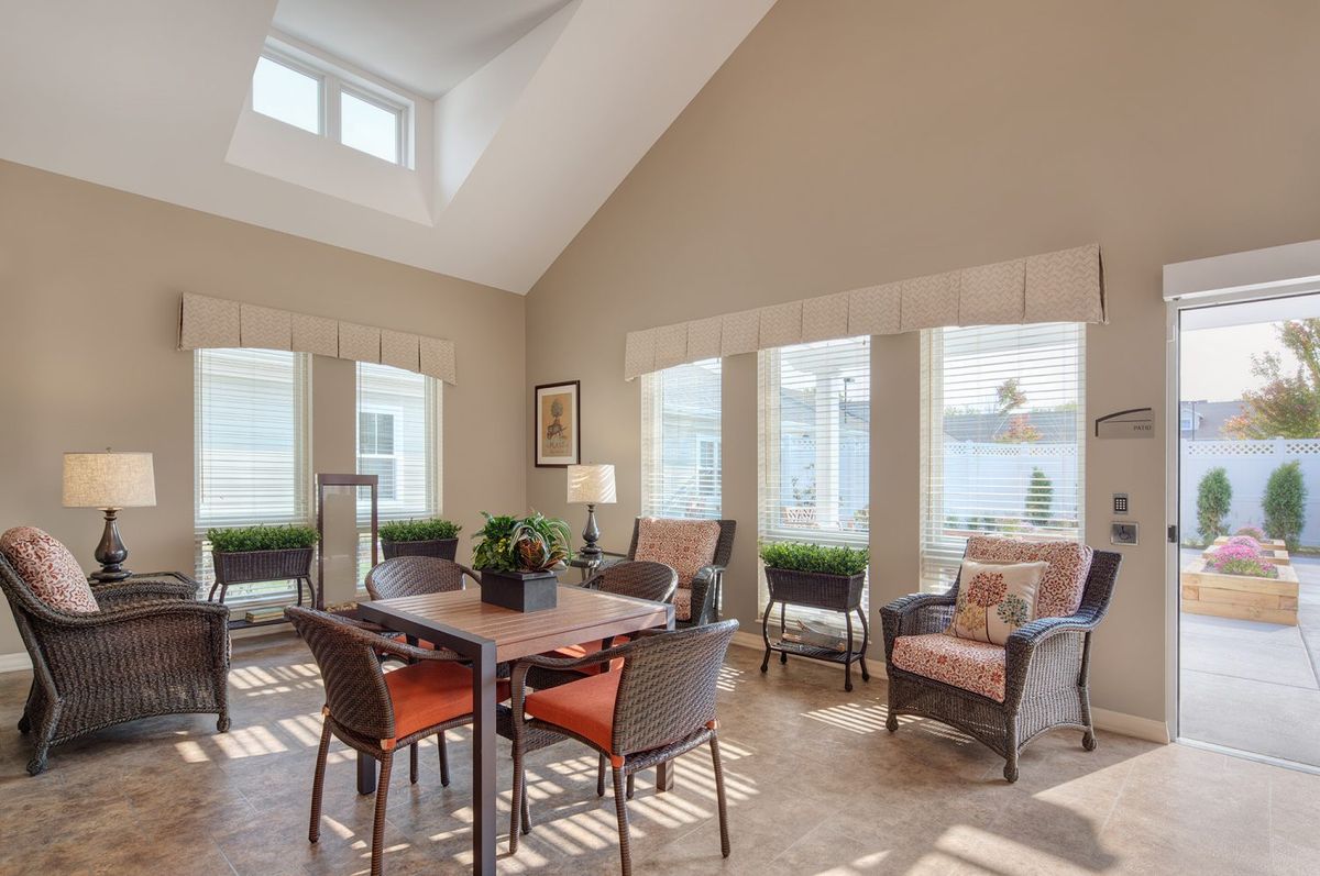 A bright and airy living room featuring a dining area with large windows and contemporary furniture.