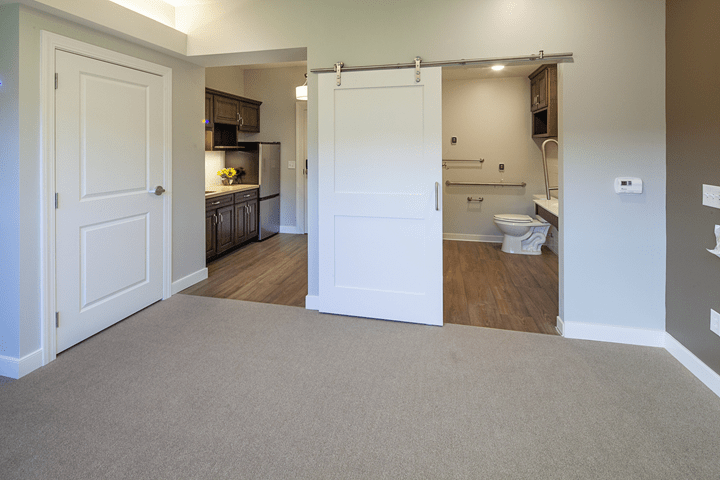 A modern living space with a kitchen and bathroom separated by a sliding door.