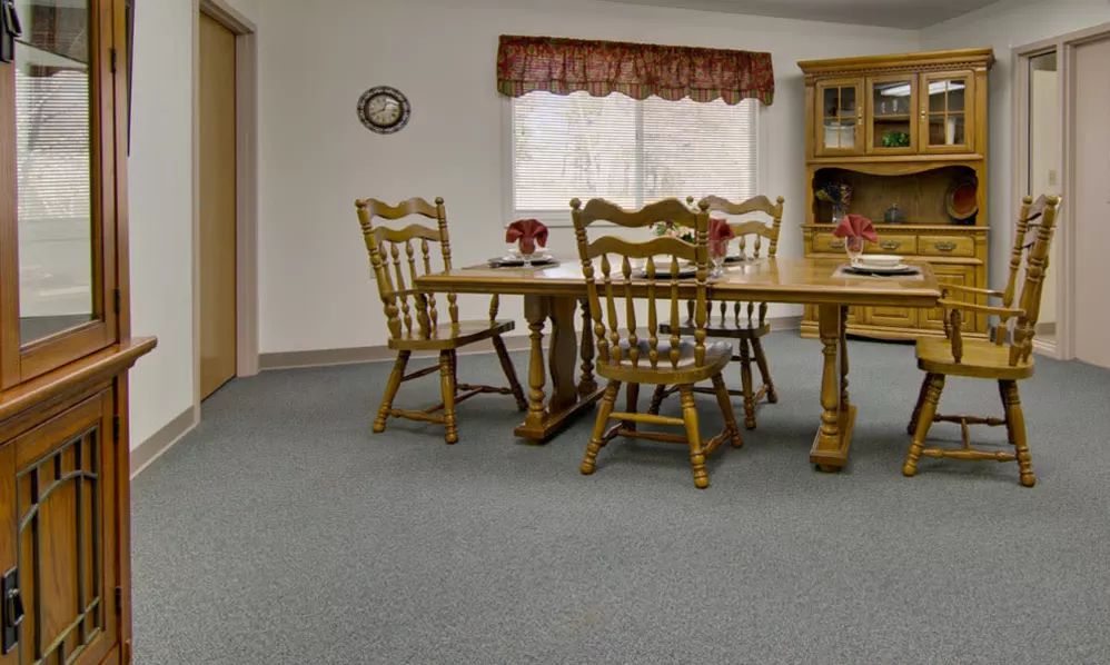 A cozy dining room with wooden furniture and a carpeted floor.
