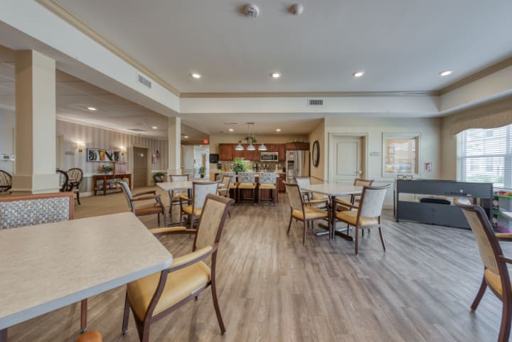 A spacious and well-lit dining area with tables and chairs on hardwood flooring.