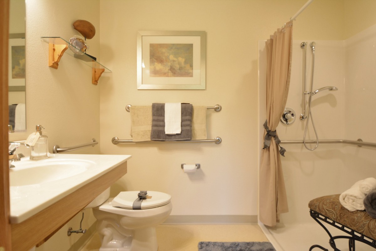 A cozy, well-lit bathroom featuring a shower with a curtain, wall art, a sink, and neatly arranged towels.
