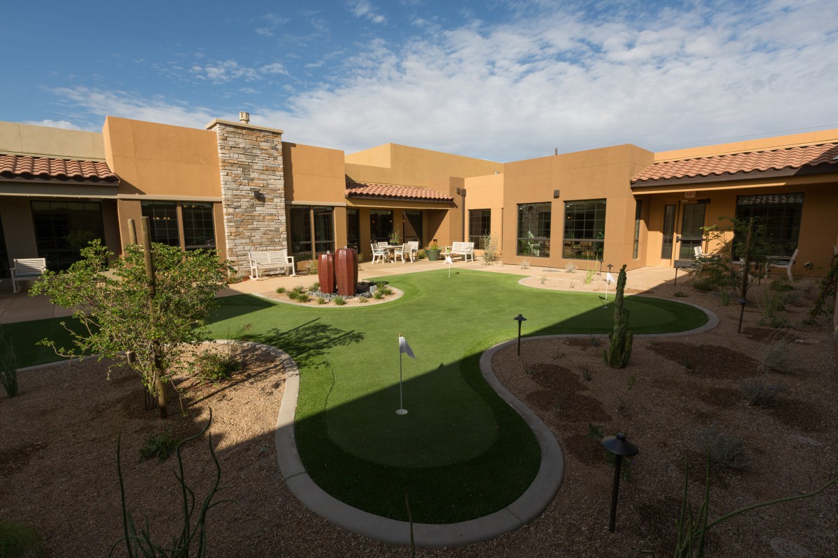 A modern desert home with a central courtyard featuring a manicured lawn and landscape.