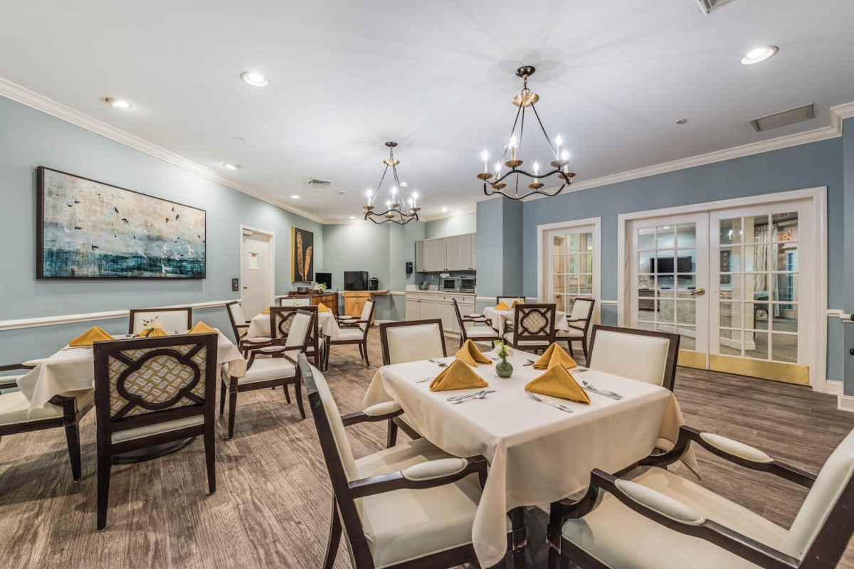 An elegant dining room with neatly set tables and chandeliers.