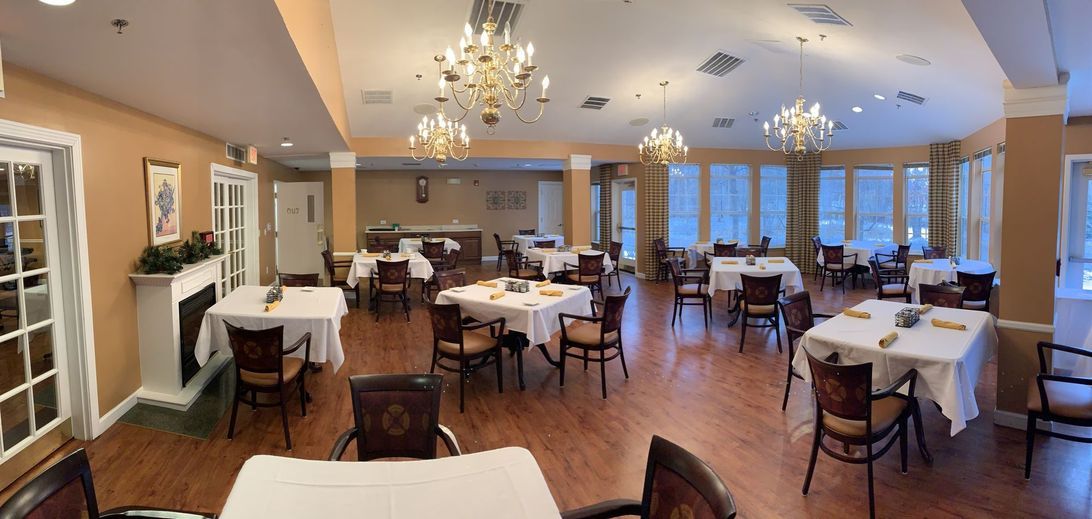 An elegant, empty dining room with neatly arranged tables and decorative chandeliers.