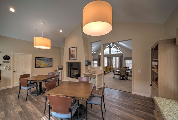 A modern dining area with wooden tables and chairs, featuring large pendant lights and wood flooring.