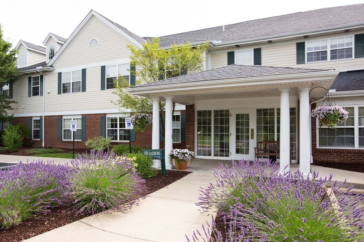 A two-story residential building with a porch and landscaped garden.