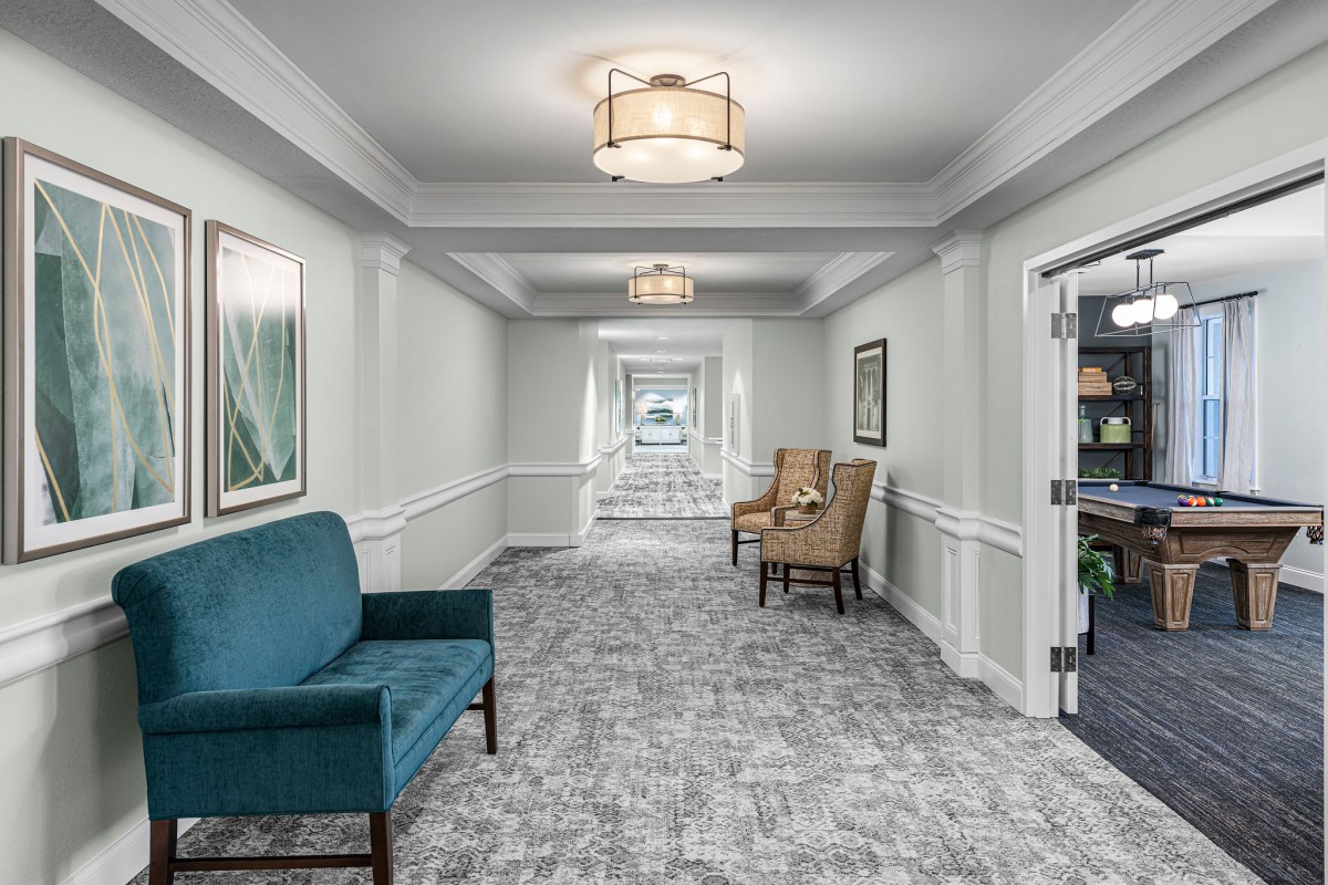 A modern hallway featuring seating areas, elegant lighting fixtures, and decorative artwork.