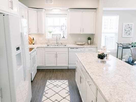 A bright and modern kitchen with white cabinets and a marble island.