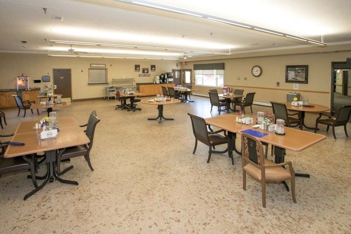 An empty dining room with neatly arranged tables and chairs in a community space.