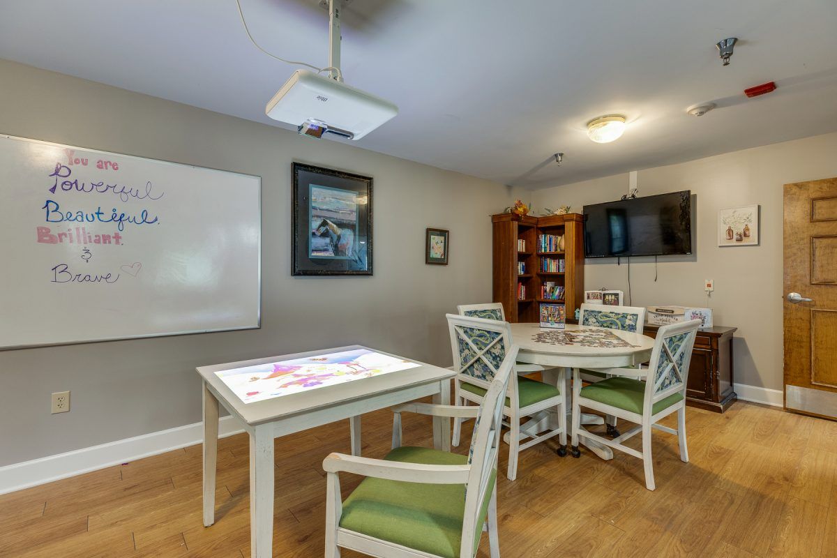 A well-organized study room featuring a table with chairs, a whiteboard, and a projector.