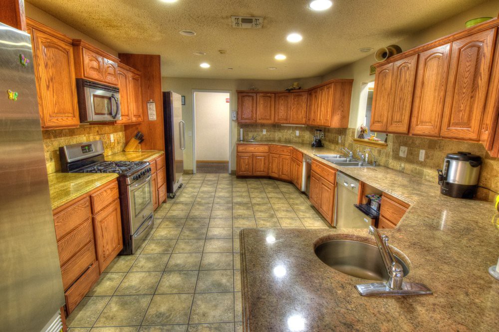 A spacious kitchen with wooden cabinets, tiled floor, and modern appliances.