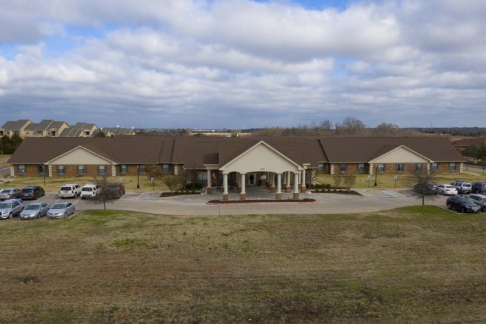 A large residential building with a driveway and a cloudy sky overhead.