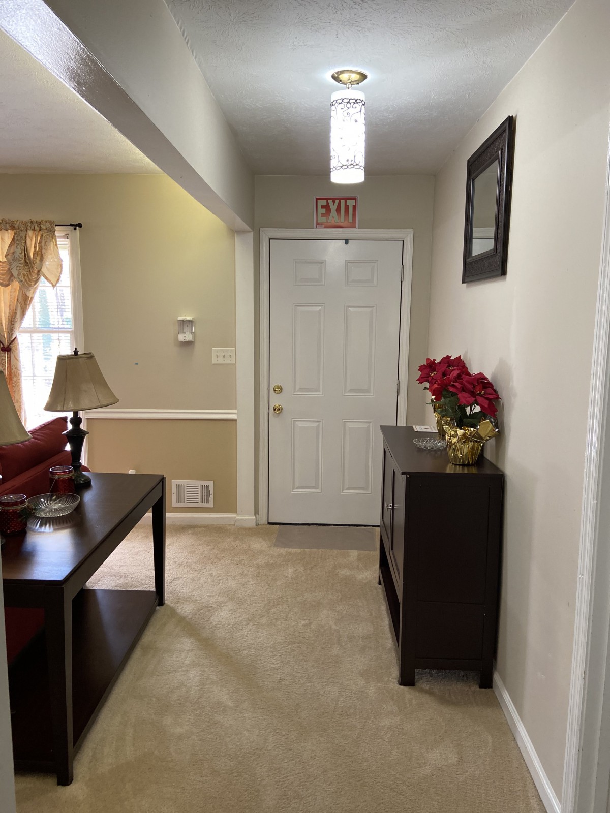 A cozy hallway with a table, lamp, and floral arrangement near the entrance.