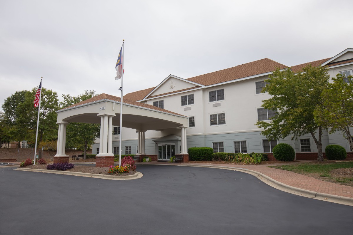 A hotel building with a covered entrance and an American flag in the foreground.