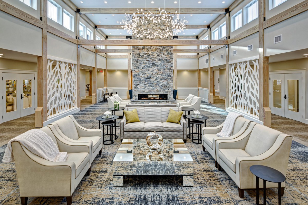 A luxurious and spacious living room featuring a central stone fireplace, elegant sofas, and a stunning chandelier.