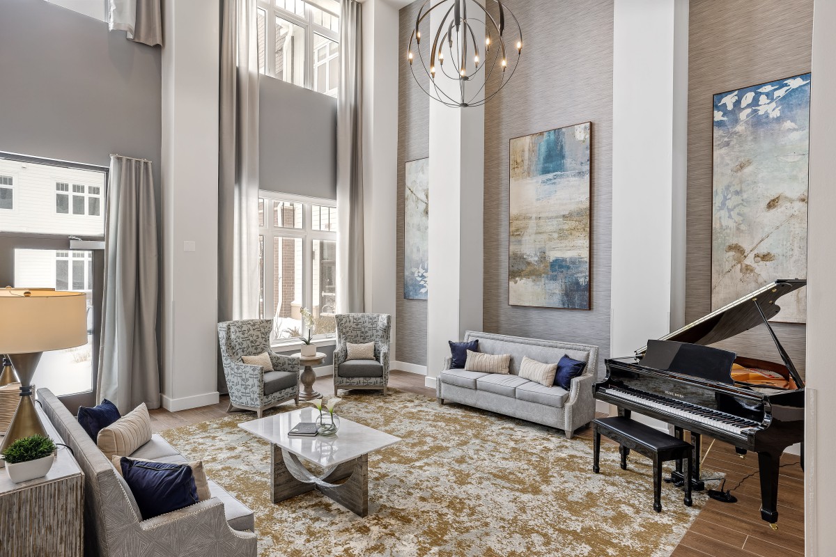 A modern living room with high ceilings featuring a grand piano, stylish furniture, and large windows.