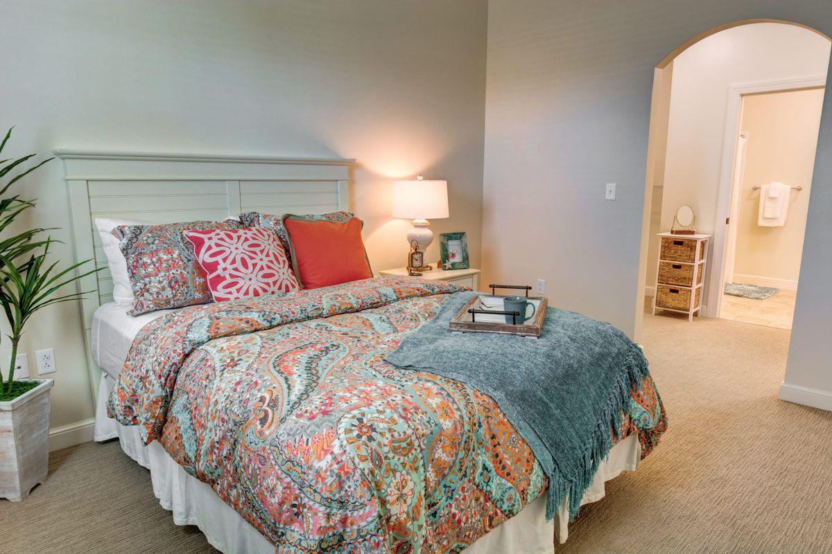 A cozy bedroom with a well-decorated bed featuring colorful pillows and a patterned comforter.