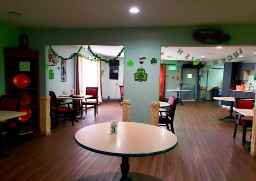 A cozy interior of a restaurant featuring green decorations and empty seating.