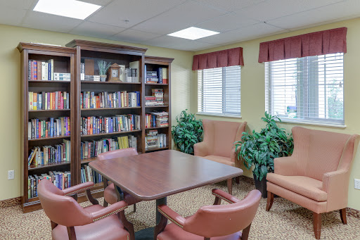 A cozy reading and meeting area featuring bookshelves, comfortable seating, and indoor plants.