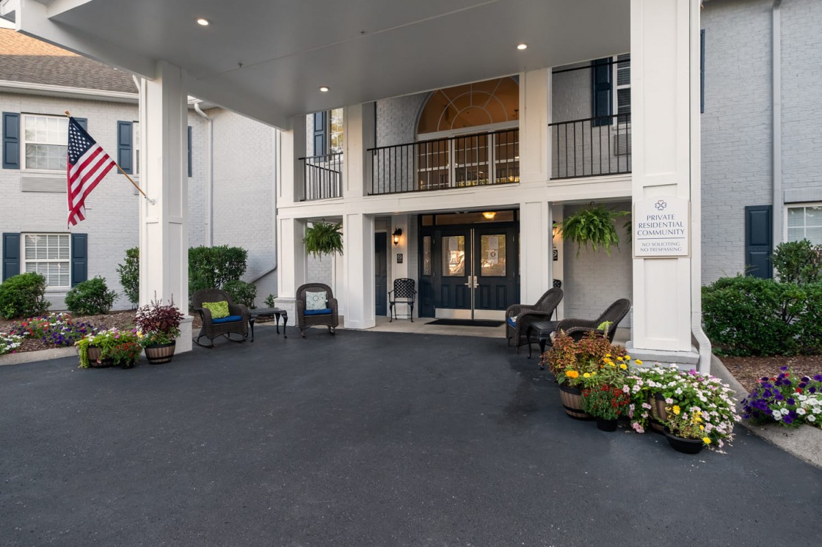 A hotel entrance with outdoor seating and decorative plants.