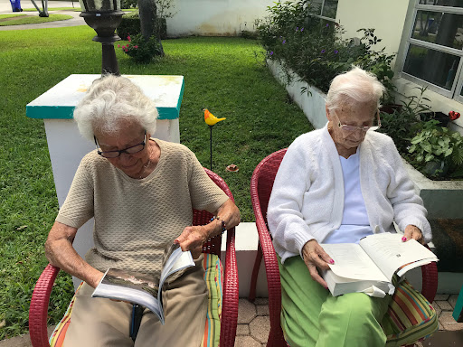 Two elderly women enjoying a peaceful afternoon reading in the garden.