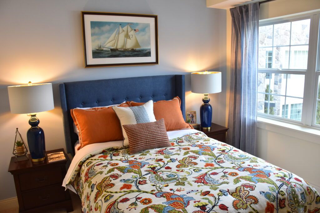 A cozy bedroom featuring colorful bedding, a blue headboard, and elegant decor.