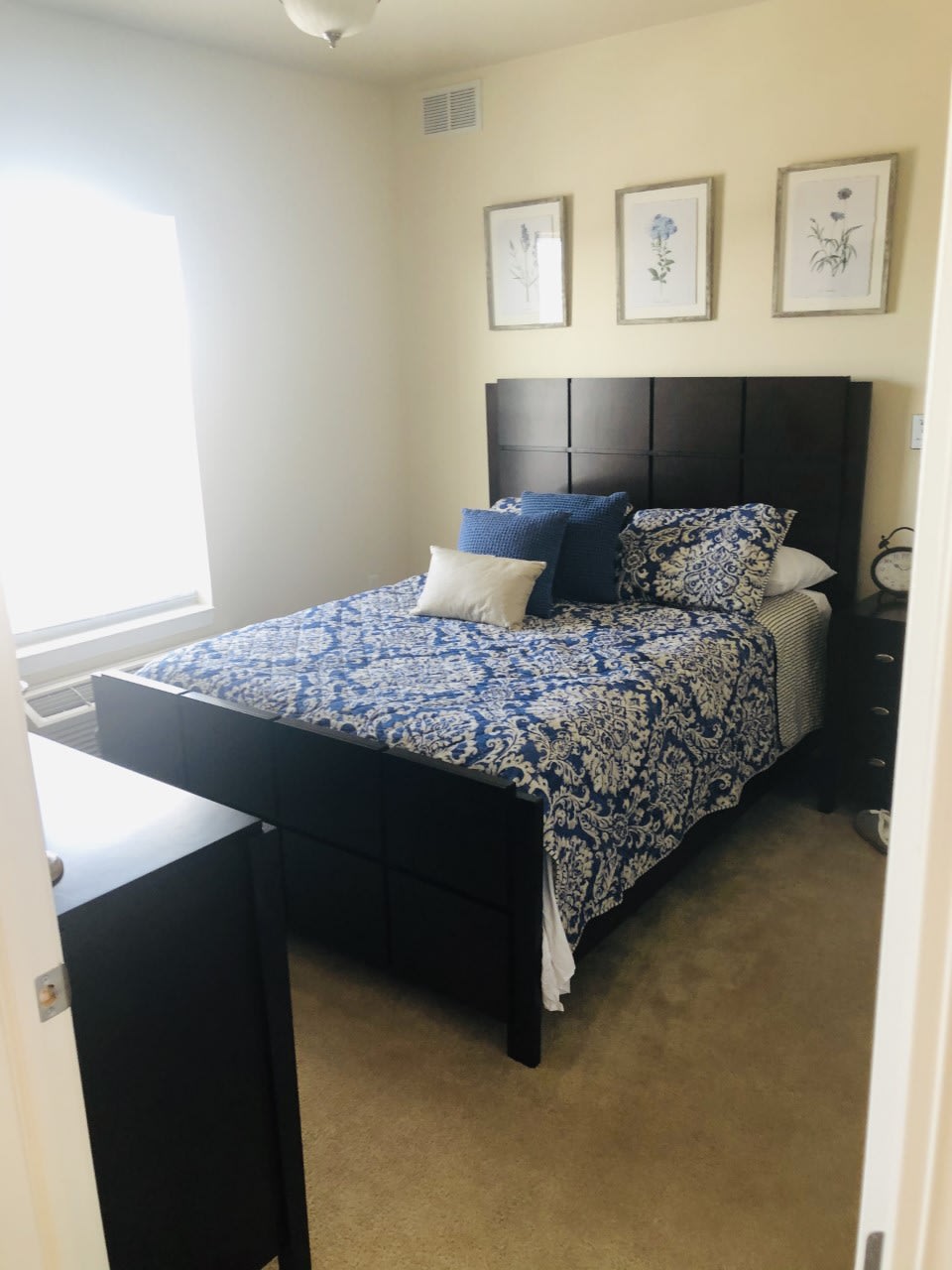 A cozy, well-decorated bedroom with a bed, pillows, and framed art on the wall.