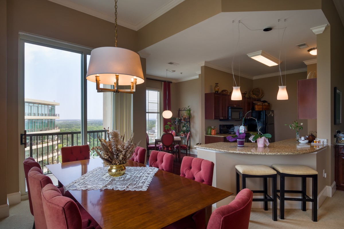 A modern dining area adjacent to a kitchen, featuring stylish lighting and comfortable seating.