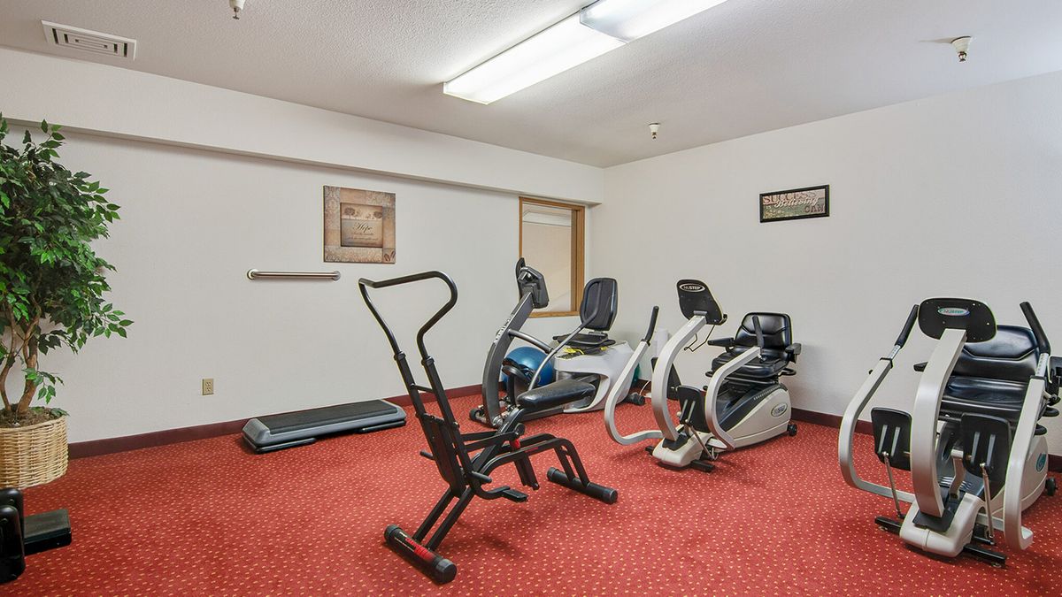 A small gym with cardio equipment including an elliptical machine and a stationary bike.