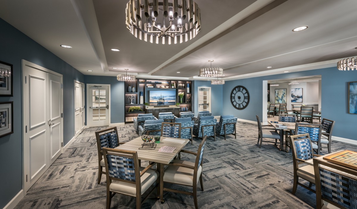 A modern dining room with elegant chandeliers, featuring blue walls and comfortable seating.