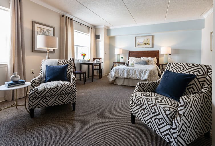 A cozy bedroom with patterned chairs, a comfortable bed, and elegant decor.