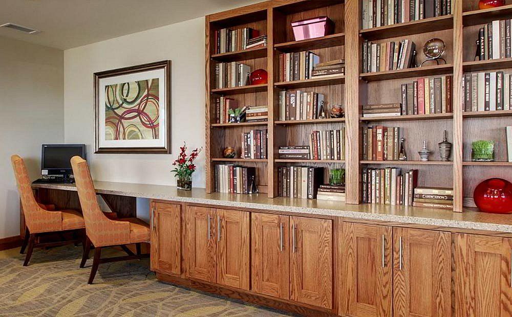 A cozy home office space featuring a large wooden bookshelf filled with books.
