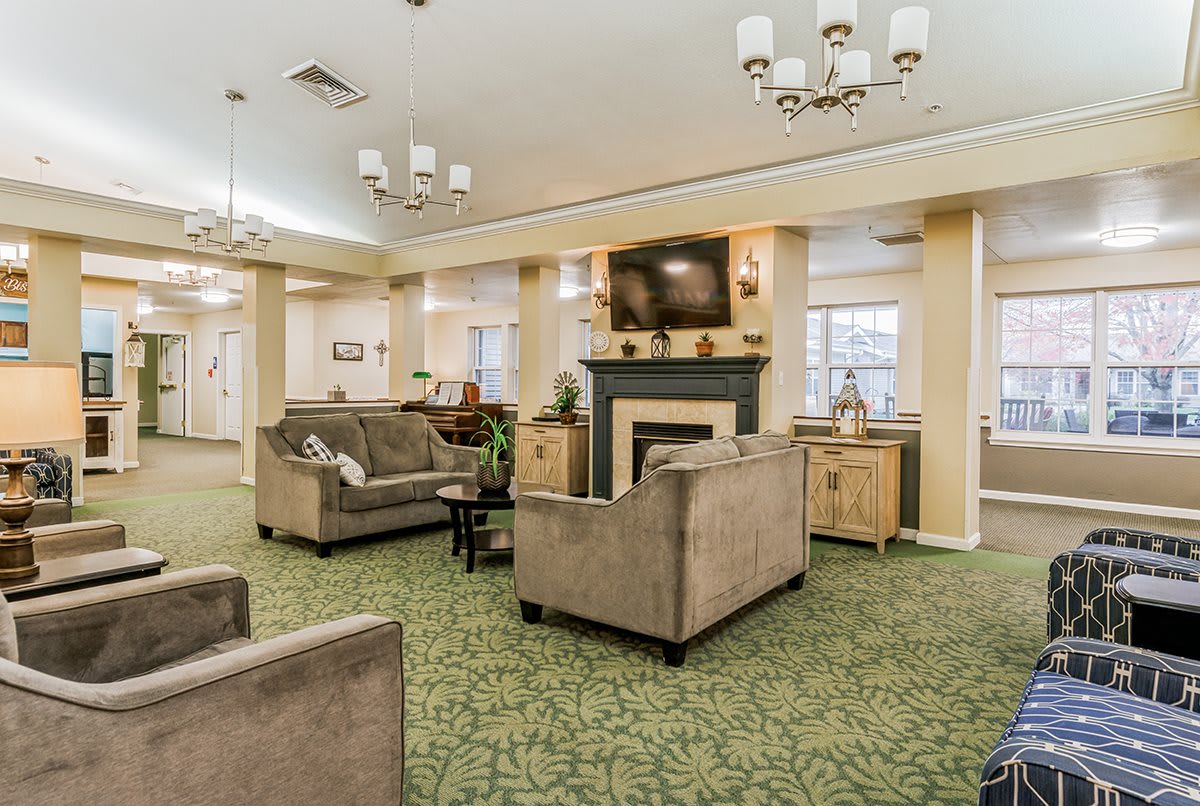 A cozy living room with sofas, a fireplace, and elegant chandeliers.