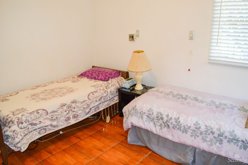 A cozy bedroom with two single beds, a nightstand, and a lamp.