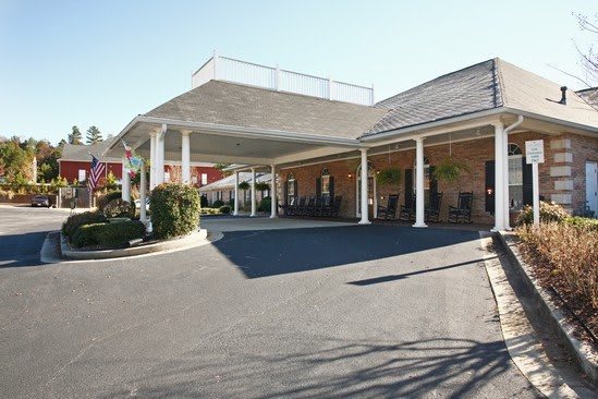 The image shows the exterior entrance of a hotel with a covered driveway and columns.