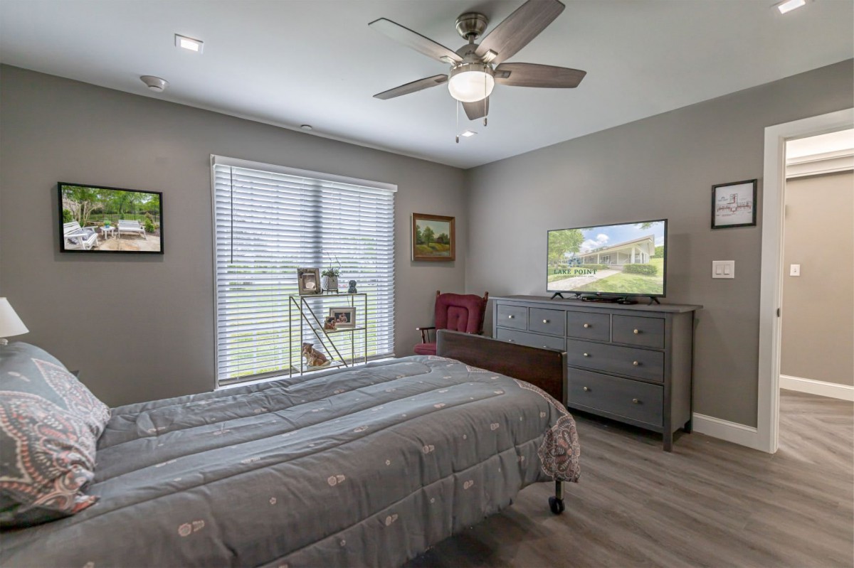 A cozy bedroom features a bed, dresser, and ceiling fan with natural light streaming through the window.