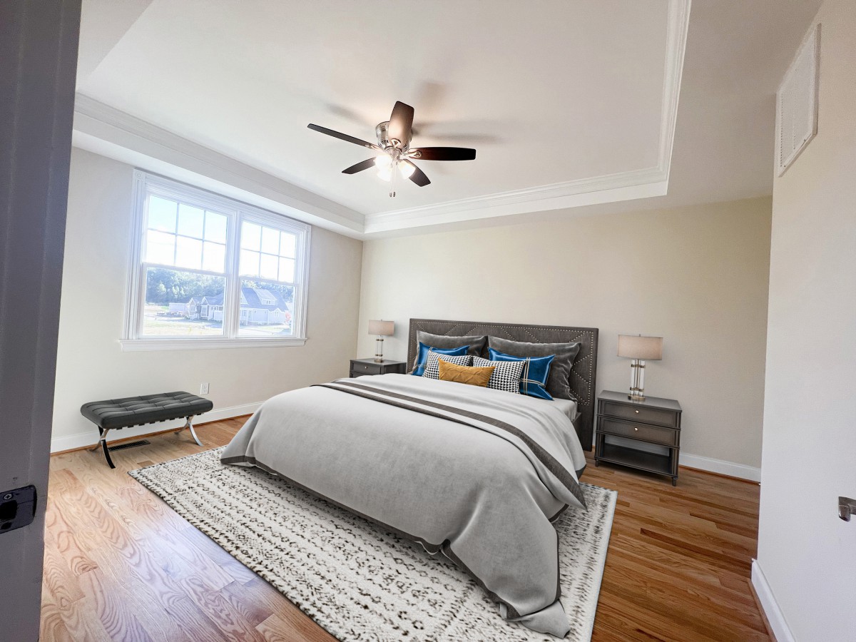 A modern bedroom featuring a large bed with neutral bedding, a ceiling fan, and ample natural light from the window.