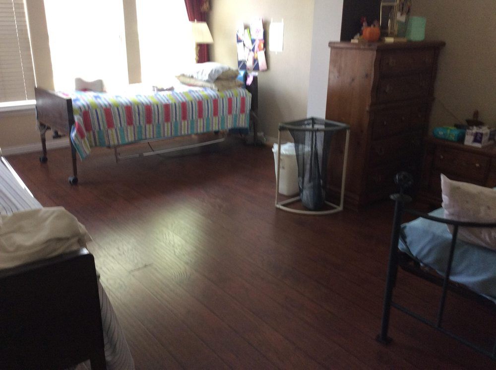 A tidy bedroom with a neatly made bed and wooden floors.