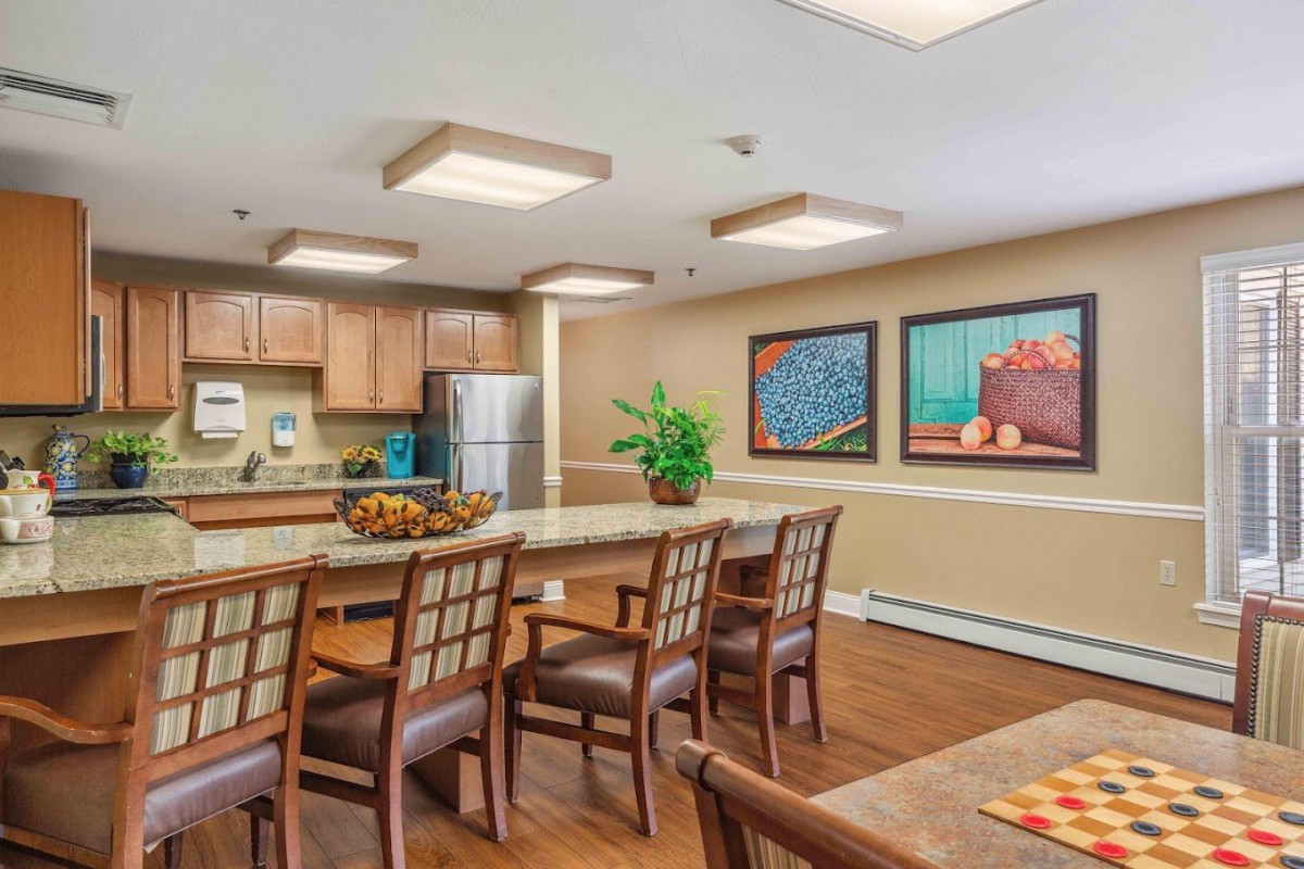 A modern kitchen and dining area featuring a large table with chairs, wooden cabinetry, stainless steel appliances, and decorative artwork on the walls.