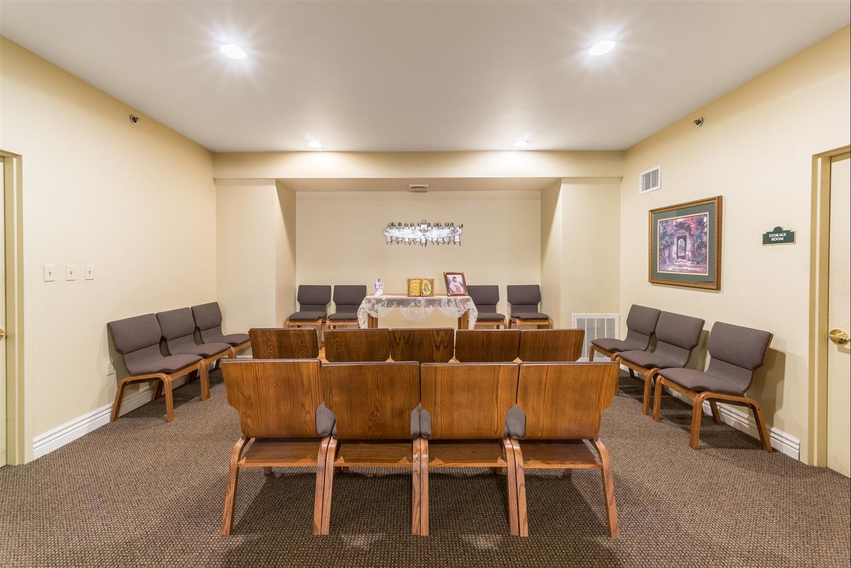 A small meeting room with rows of wooden chairs and a table at the front.