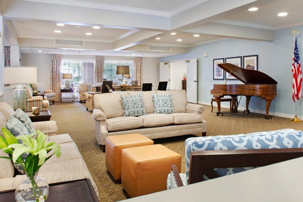 A spacious and elegantly decorated living room featuring comfortable sofas and a grand piano.