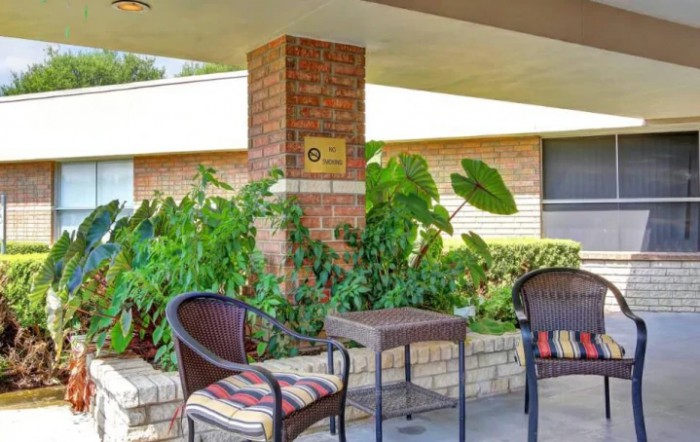 A cozy outdoor patio with chairs, a table, and lush greenery.