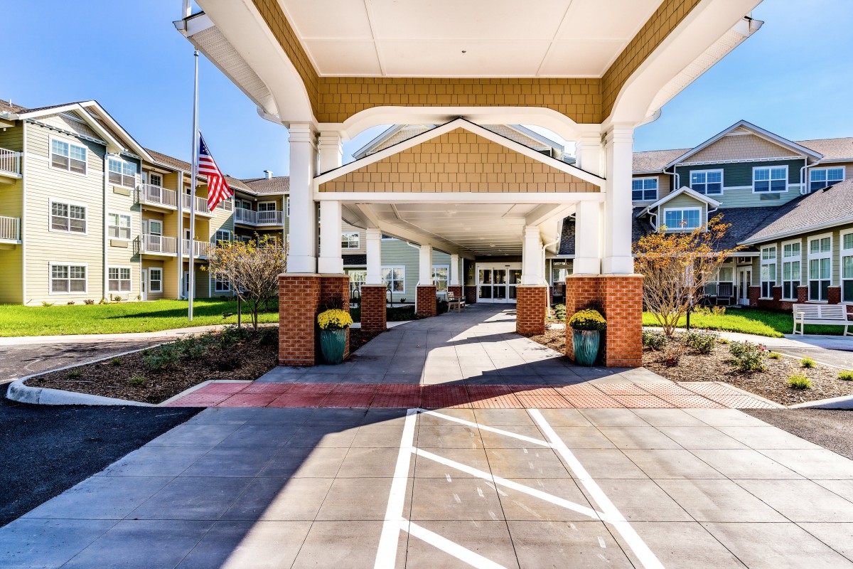 Elegant building entrance with a covered walkway and landscaped surroundings.