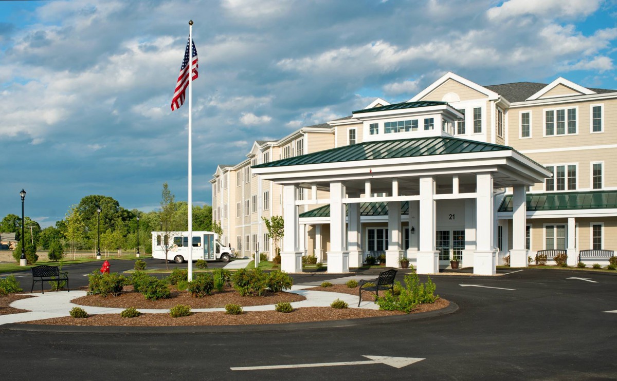 A hotel's entrance with an American flag and landscaped surroundings.