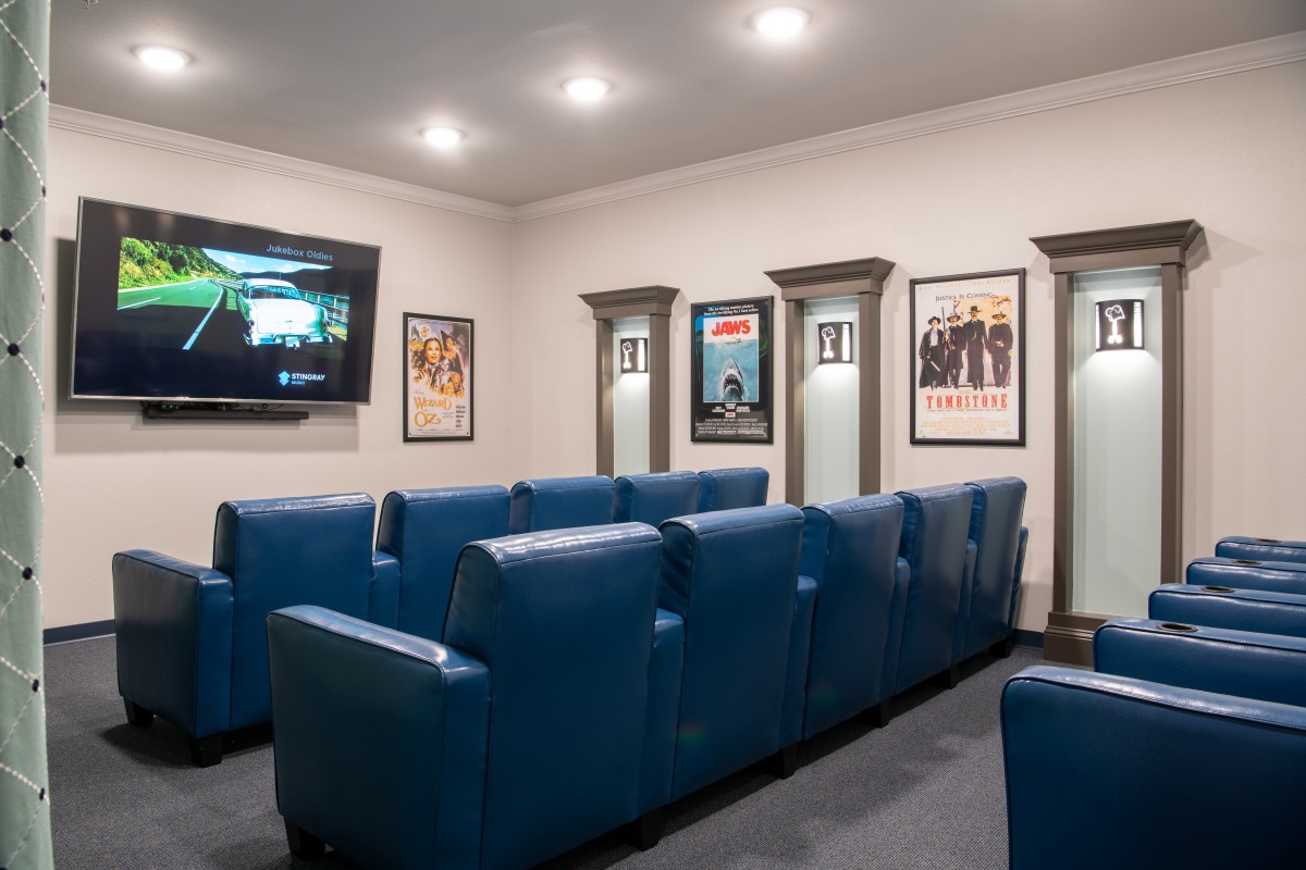 A cozy home theater with blue seating and movie posters on the walls.