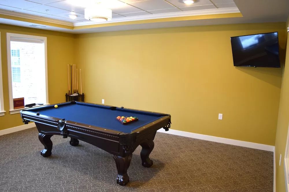 A recreation room featuring a pool table and a mounted TV on the wall.