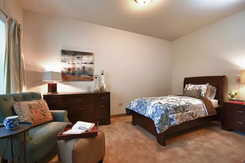 A cozy bedroom with a single bed, armchair, and decor.
